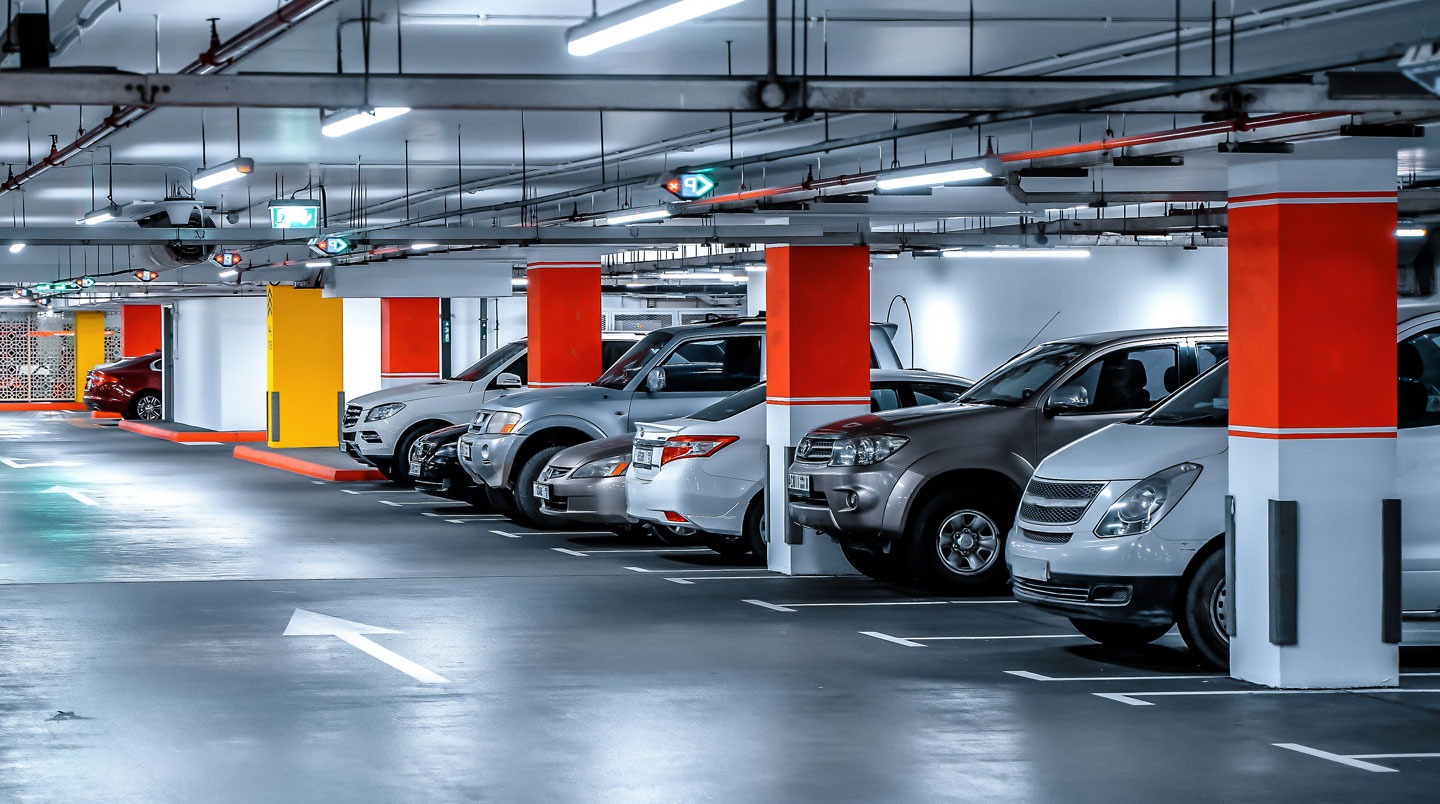 Vue grand angle d'un parking extérieur sécurisé moderne avec barrières automatiques et signalétique claire, sans présence humaine au premier plan